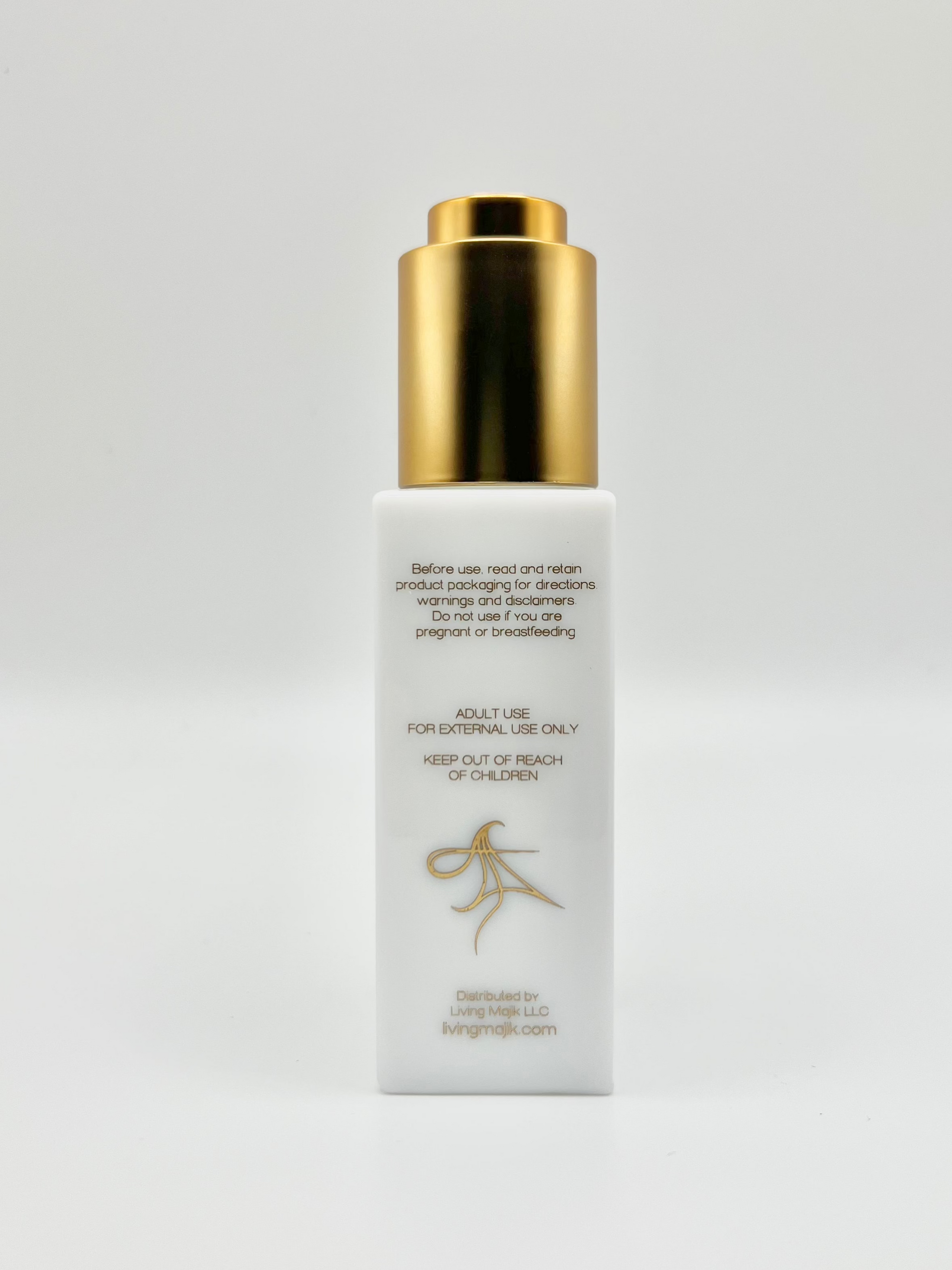 Picture of the back of Livingmajik's Nourishing Botanical Facial Serum white opal glass bottle with luxury gold dropper.